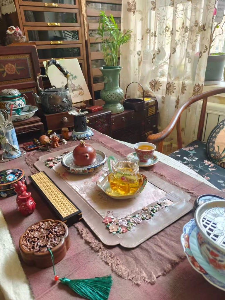 Dusty-rose leather tea mat with 3D flowers, zisha pot on a silver tray.